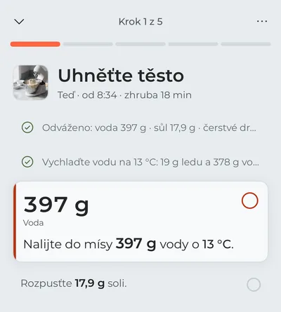 Režim vaření na prvním kroku, „Uhněťte těsto“: odvážení surovin a vychlazení vody jsou odškrtnutá a zvýrazněná je voda, kterou teď nalijete, s gramy velkým písmem.