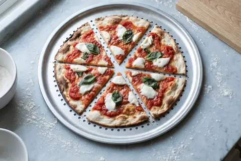 A very thin, flat pizza with no raised rim, cut into six slices on a round perforated tray.