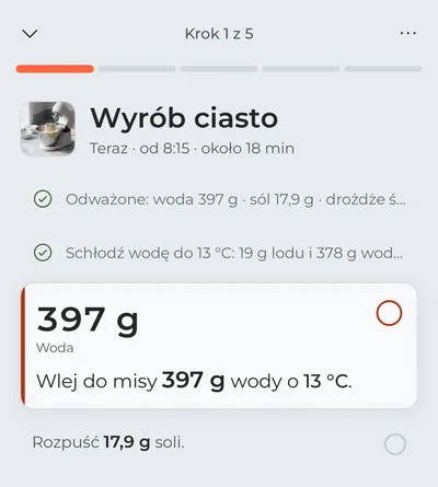 Tryb gotowania na pierwszym kroku, „Wyrób ciasto”: odważenie składników i schłodzenie wody są już odhaczone, a na pierwszym planie jest woda do wlania teraz, z gramami dużą czcionką.